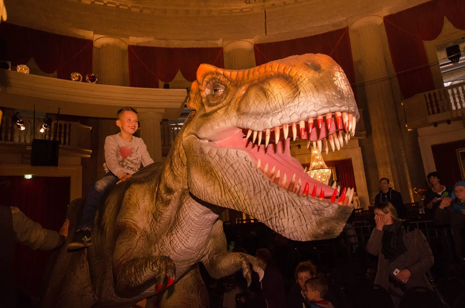 Die lebendige Dinosaurier Show, ein Kind reitet auf einem Dinosaurier-Rücken