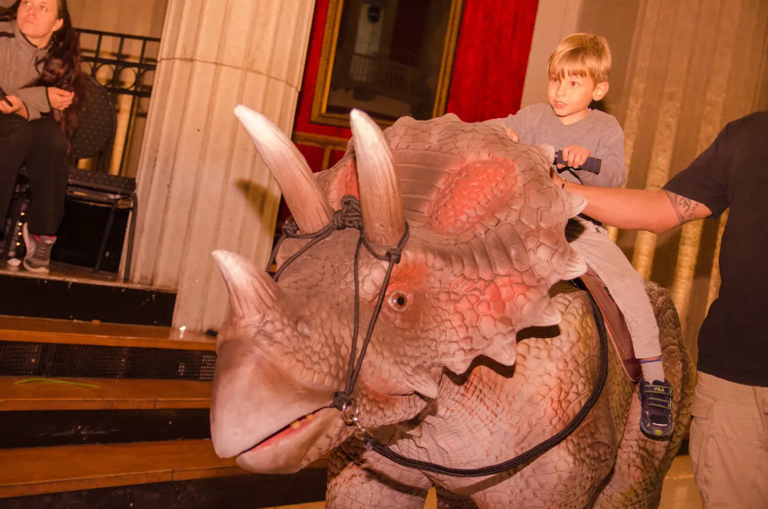 Die lebendige Dinosaurier Show, ein Kind reitet auf einem Dinosaurier-Rücken